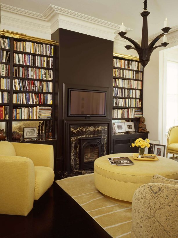 modern library living room with chocolate brown bookshelves and fireplace with blonde yellow sofa color ideas
