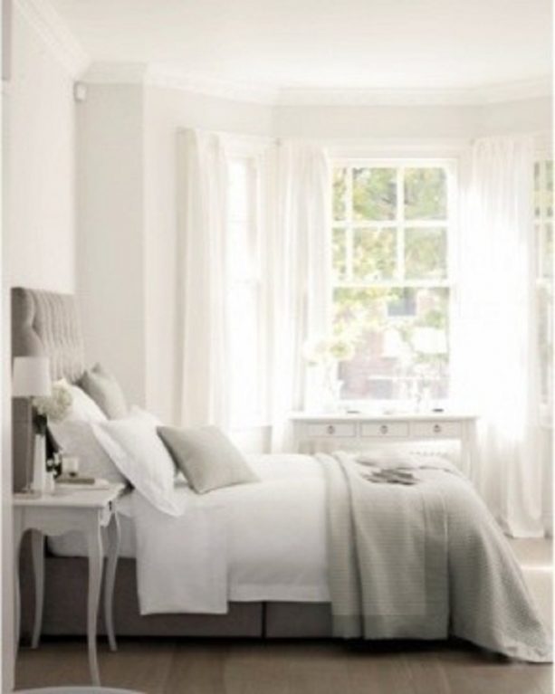 a bedroom with grey bed and white wall