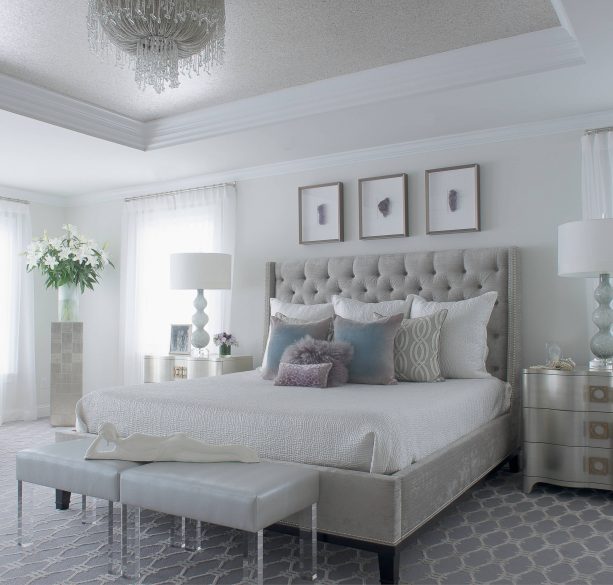 a bedroom with grey bed, white wall, and silver-colored furniture