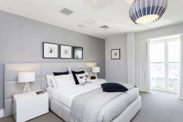 a bedroom with grey wall, white furniture, and grey carpet floor