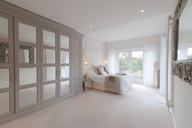 a grey and white bedroom with cream white carpet floor