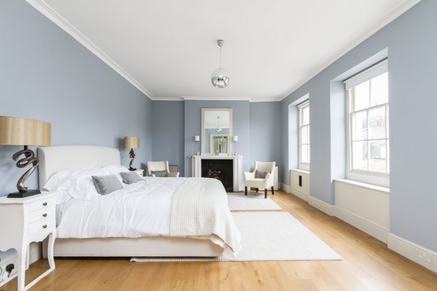a grey and white bedroom with light hardwood floor