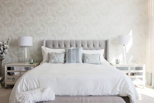 a grey and white bedroom with white mirrored bedside tables