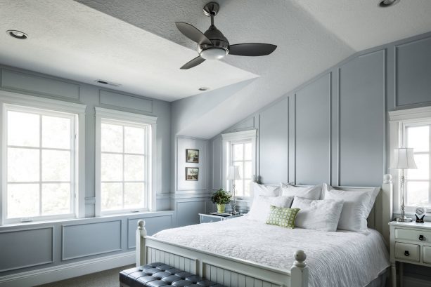 grey and white bedroom with green accent pillow and a potted indoor plant