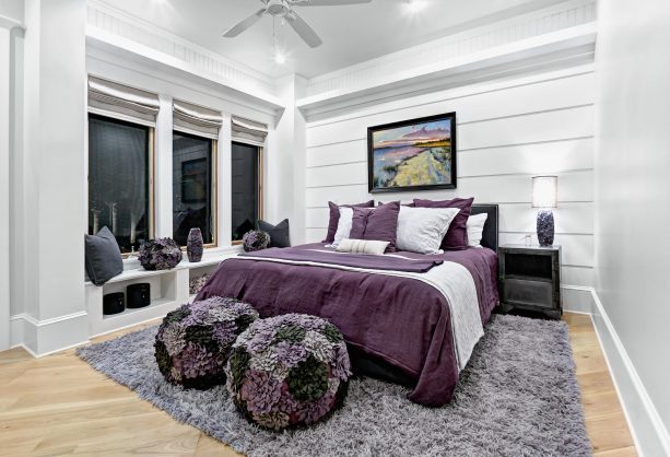 purple and grey beach-style bedroom with fluffy rug and ottomans