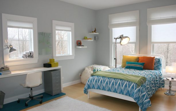 a cool blue and grey bedroom with warm-colored accent pillows