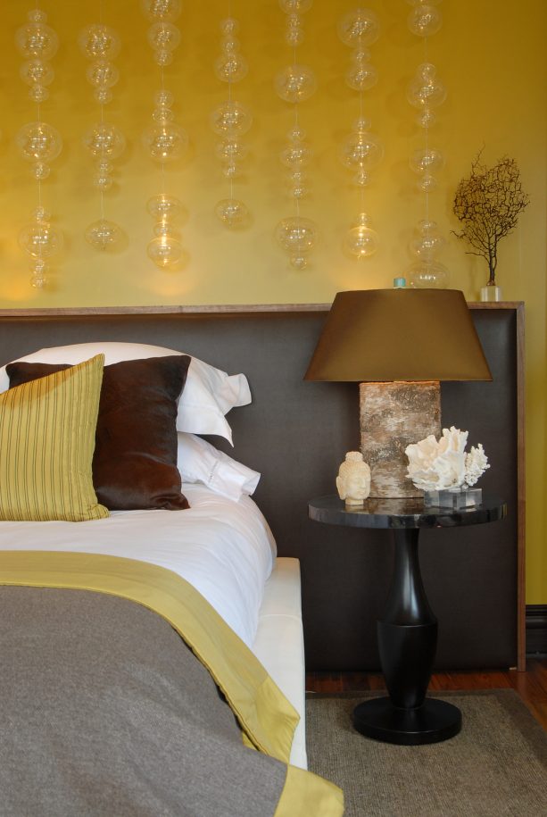 grey and yellow room with oversized leather headboard