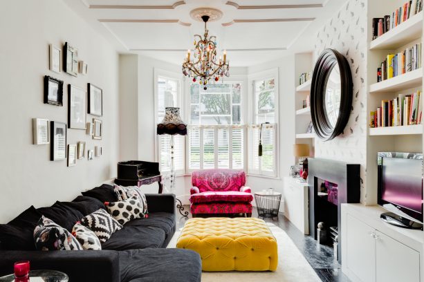 a living room with charcoal grey sectional couch and mustard yellow tufted upholstered table