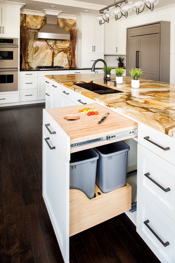 white shaker kitchen cabinets with integrated trash bins and cutting board