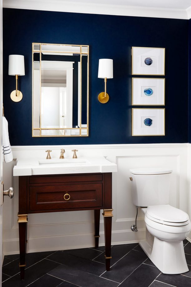 a powder room with navy blue walls and gold accents