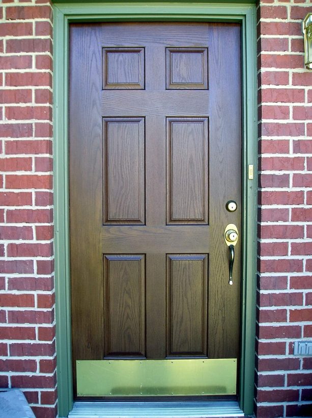 a brown-stained front door with fern green trim