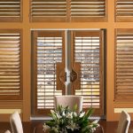 plantation shutters from medium hardwood material on white French doors