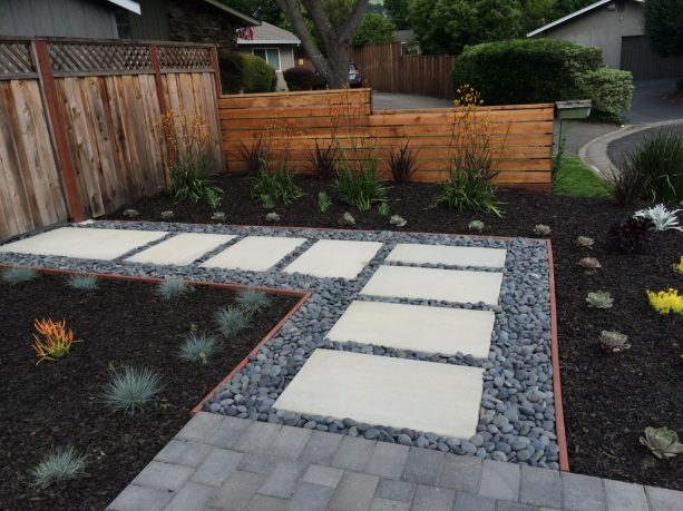 the use of black mulch and river rocks in a modern pathway landscape