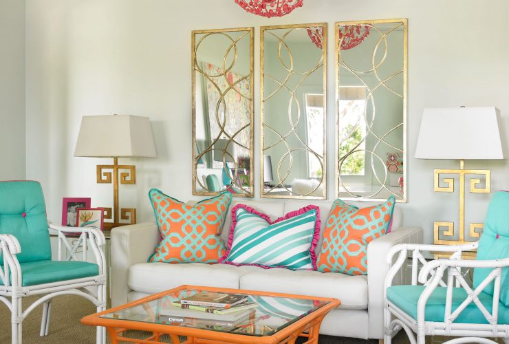 a contemporary living room with turquoise chairs and gold mirror