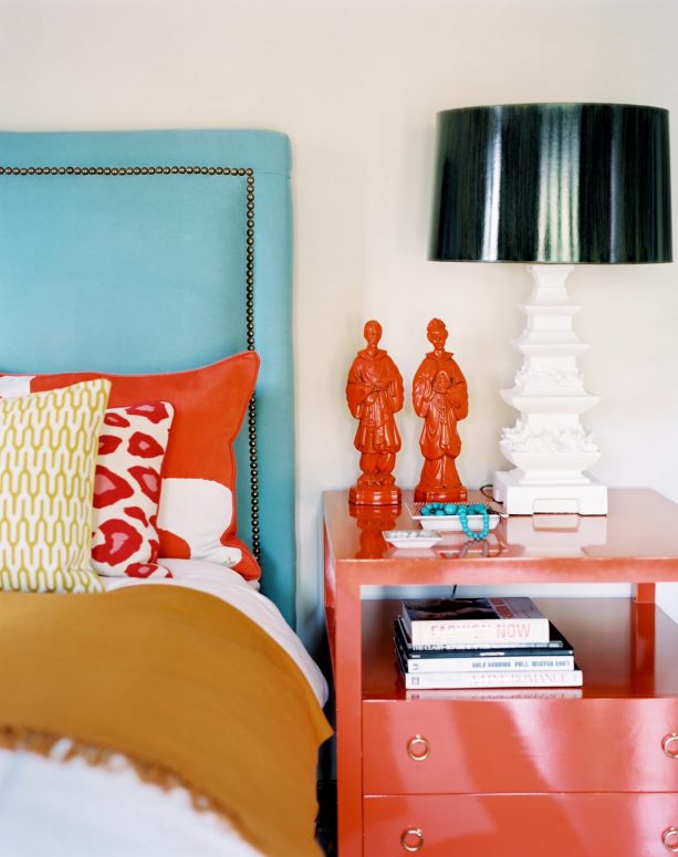 a turquoise headboard paired with tangerine bedside table and decorations