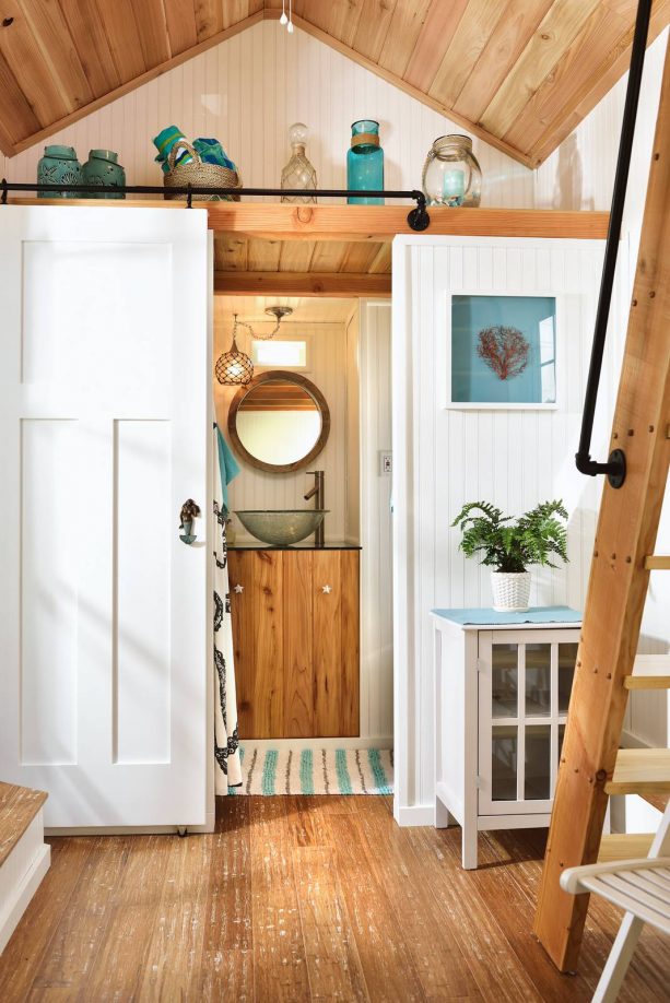 a small bathroom with barn door in a tiny beach house