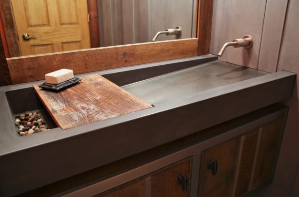 a contemporary concrete bathroom sink with colorful rocks on the drain