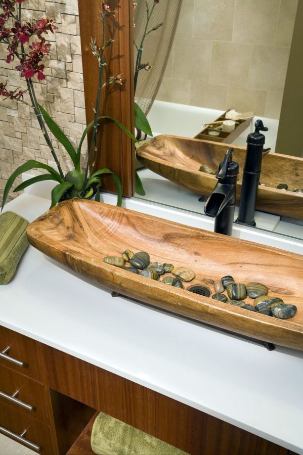 a long Asian wooden sink with multi-color rocks on the bottom