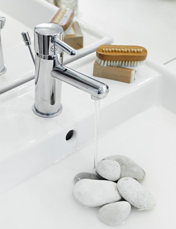 a white modern bathroom vanity sink with white river stones covering the drain