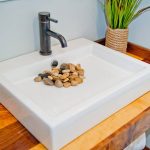 a white sink with yellow rocks covering the drain