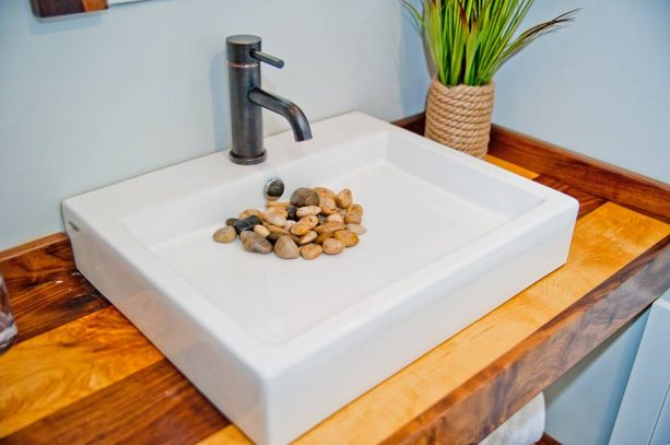 a white sink with yellow rocks covering the drain