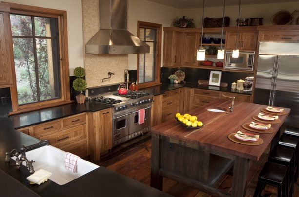 hickory cabinets, dark wood floor, black countertops, and black backsplash in an elegant kitchen