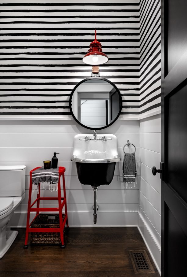 a black and white modern farmhouse bathroom with accentuating red stool