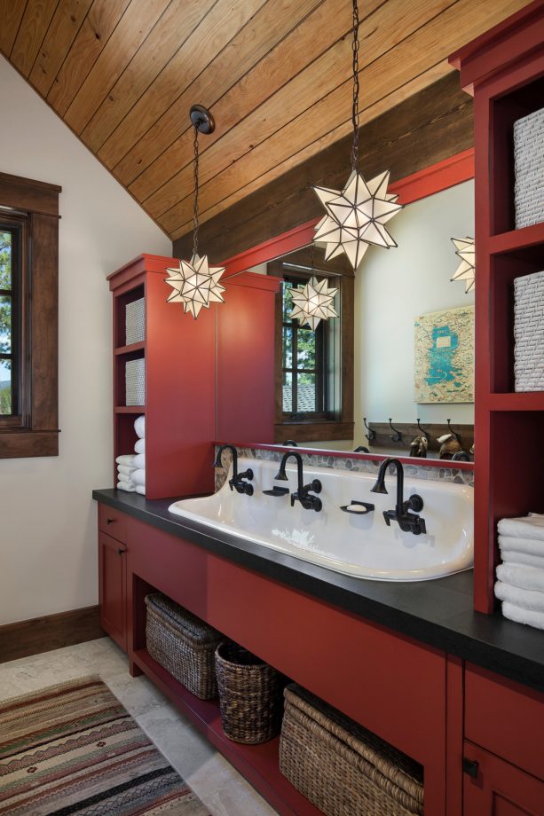 a matte red custom vanity with black countertop and hardware in a rustic bathroom