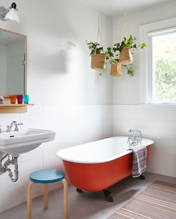 a red tub with black feet in a Scandinavian bathroom