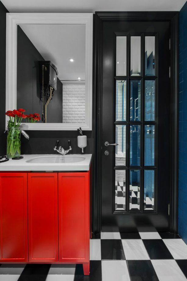 unique contemporary bathroom interior with black walls, black French door, and bright red vanity