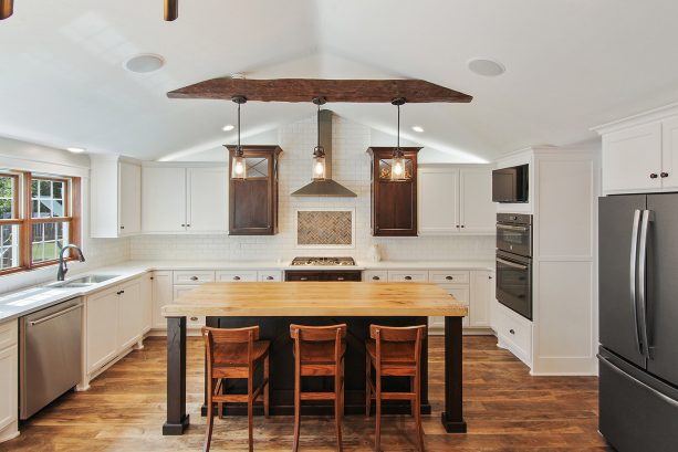 a farmhouse kitchen with slate appliances, white cabinets, and wood accents