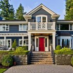 a traditional house with a timeless combination of denim blue wall and ruby red door
