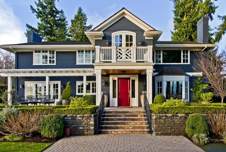 a traditional house with a timeless combination of denim blue wall and ruby red door