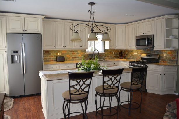 a traditional kitchen with off-white raised panel cabinets and a complete set of slate appliances