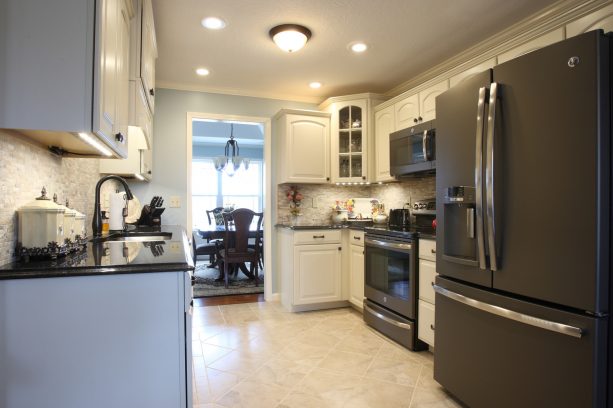 a traditional kitchen with white cabinets and black slate appliances