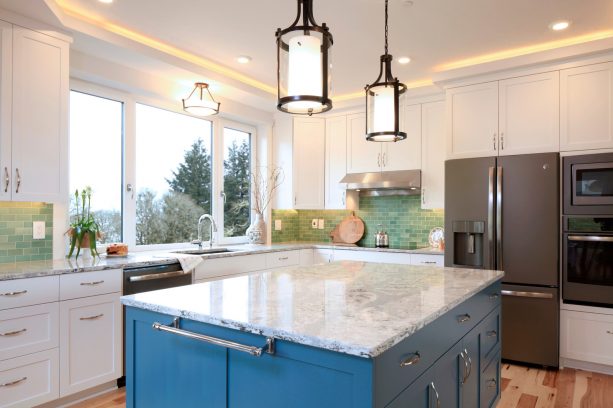 a transitional kitchen with white cabinets, slate appliances, and blue island