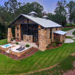 a lake house with multi-tones brick wall and white metal roof