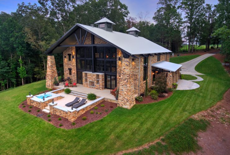 a lake house with multi-tones brick wall and white metal roof