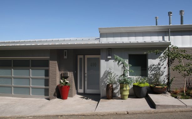 a trendy contemporary grey-painted brick house with metal roof