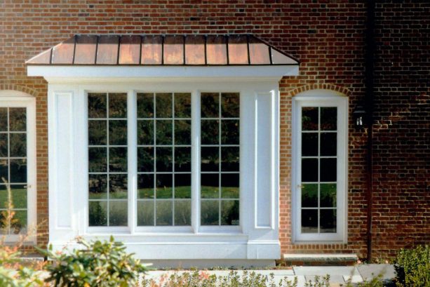 a white box bay window with metal roof in a brick house design