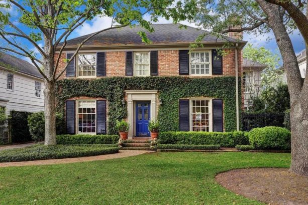 navy front door paired with black shutters in red brick home exterior
