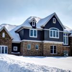 a craftsman house with half mixed brick and half navy blue siding