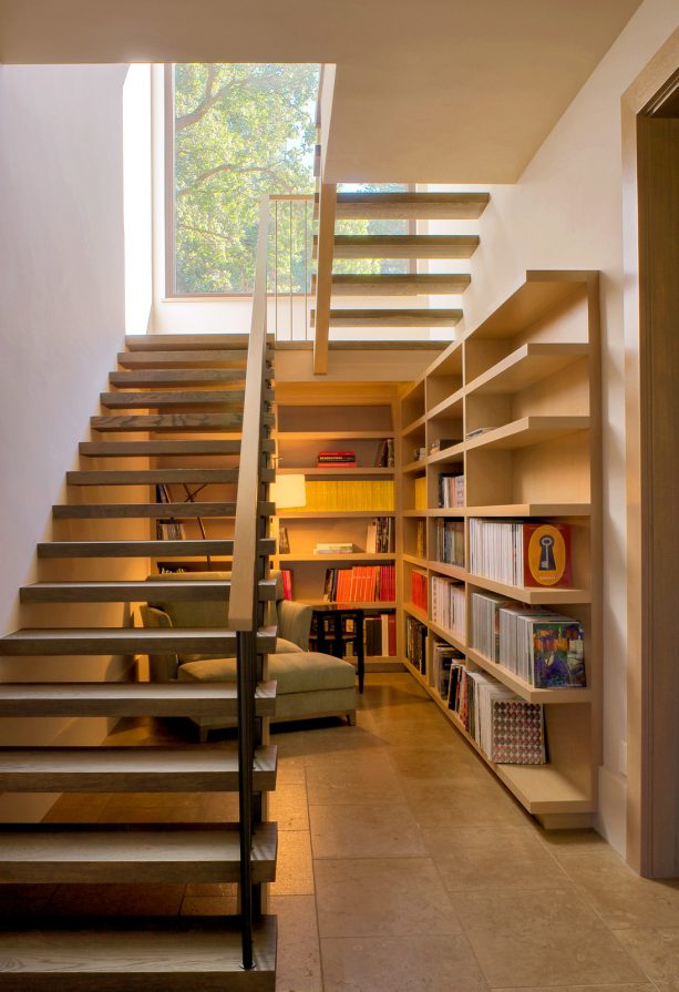 a reading area under an open staircase that leads to a basement