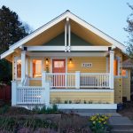 a soft yellow craftsman house with white trim, a bit of grey tone, and orange front door