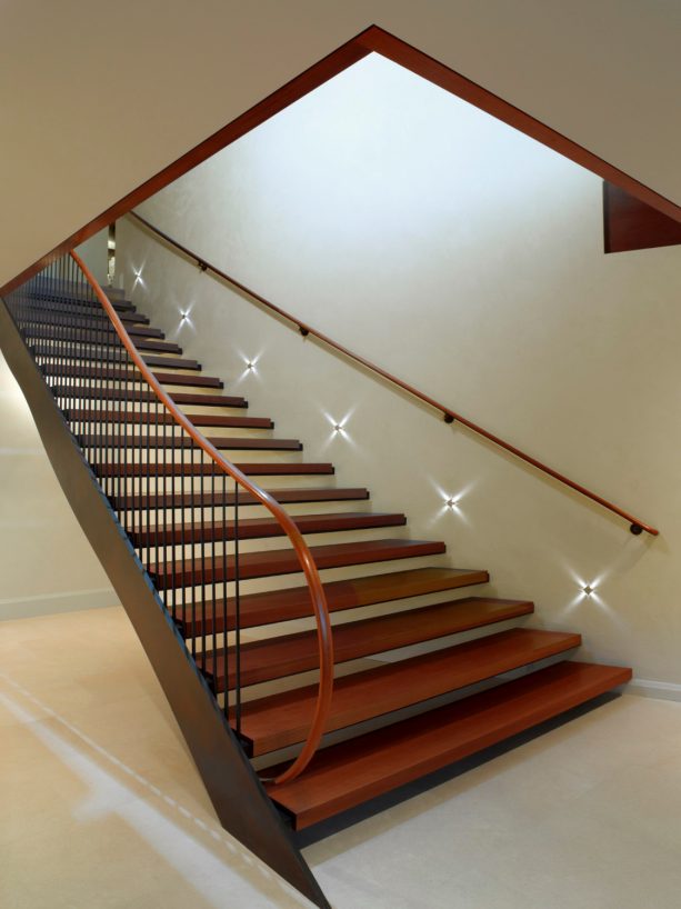 a trendy wooden open staircase paired with built-in lighting on the wall