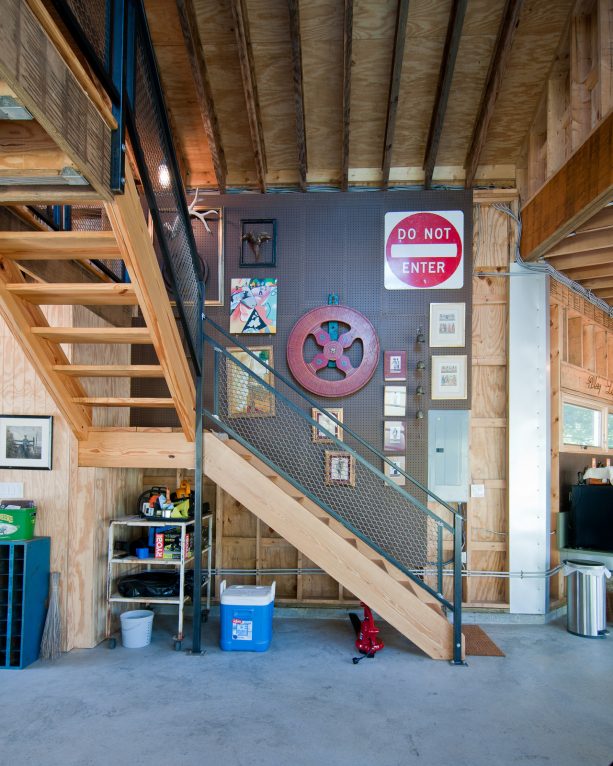 a wooden open staircase with metal rail for an industrial basement