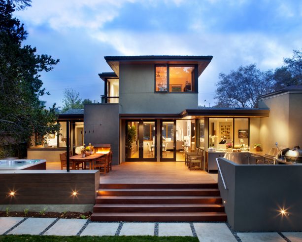 a grey stucco house with brown deck and brown doors and windows