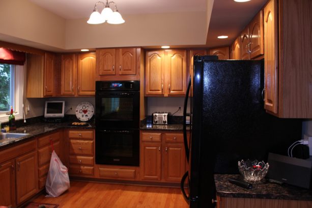 the oak cabinets are paired with black countertops and black appliances