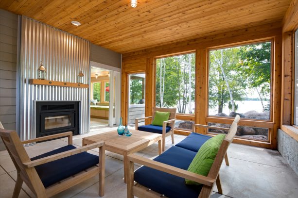 a beach-style screened porch with unique corrugated metal fireplace