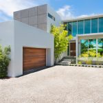 a white boxy garage in front of a beach-front contemporary house
